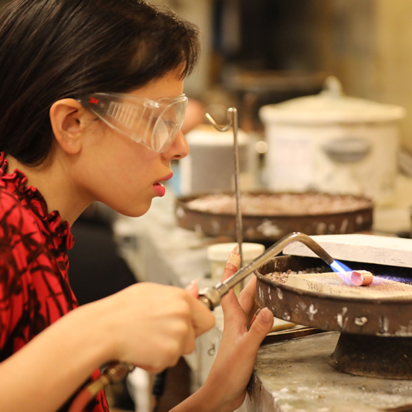 UL Lafayette metalworking student using a blowtorch on some jewelry.